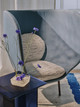 Chair upholstered in Drizzle fabric in Indigo, featuring natural base with indigo tones woven in. Wide-width Squall fabric drapes behind as a backdrop, creating a layered textured interior scene.